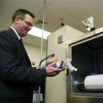 Don Stull, chief executive officer of Microzap Inc., places a loaf of bread inside a patented microwave